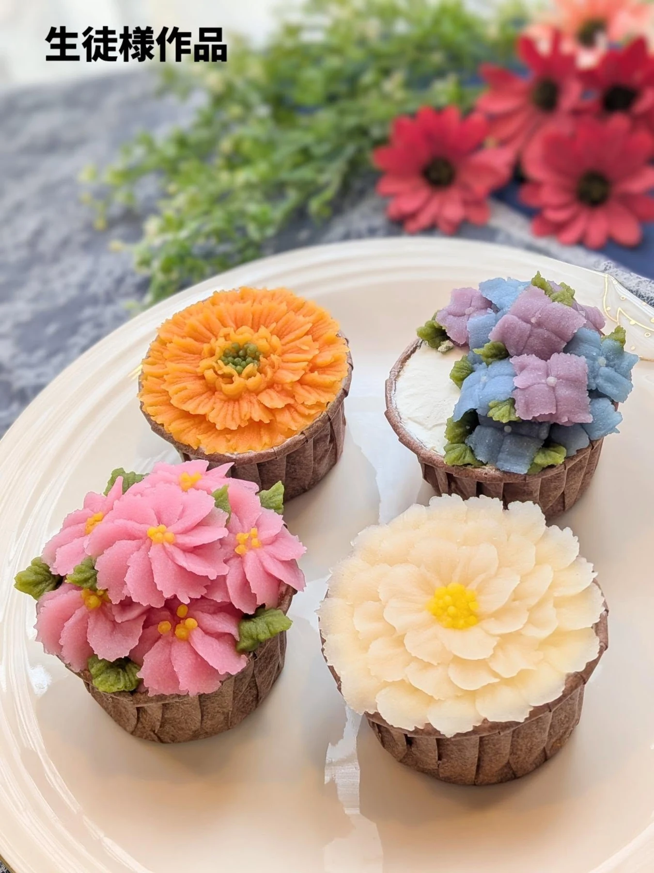 生徒さま作品。オレンジ、桃、白、紫のあんこの花を載せたカップケーキ